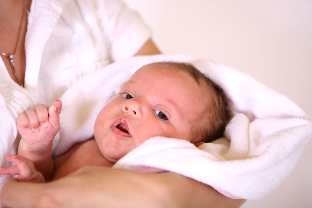 Baby i svøb der ligger i arm