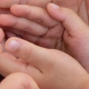 Fremstrakte hænder der holder et par barnehænder