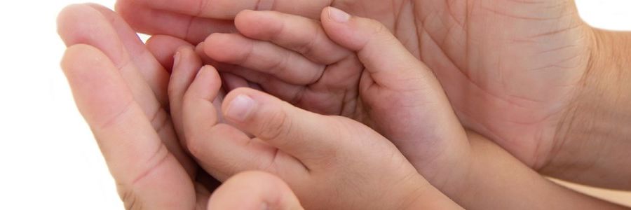 Fremstrakte hænder der holder et par barnehænder