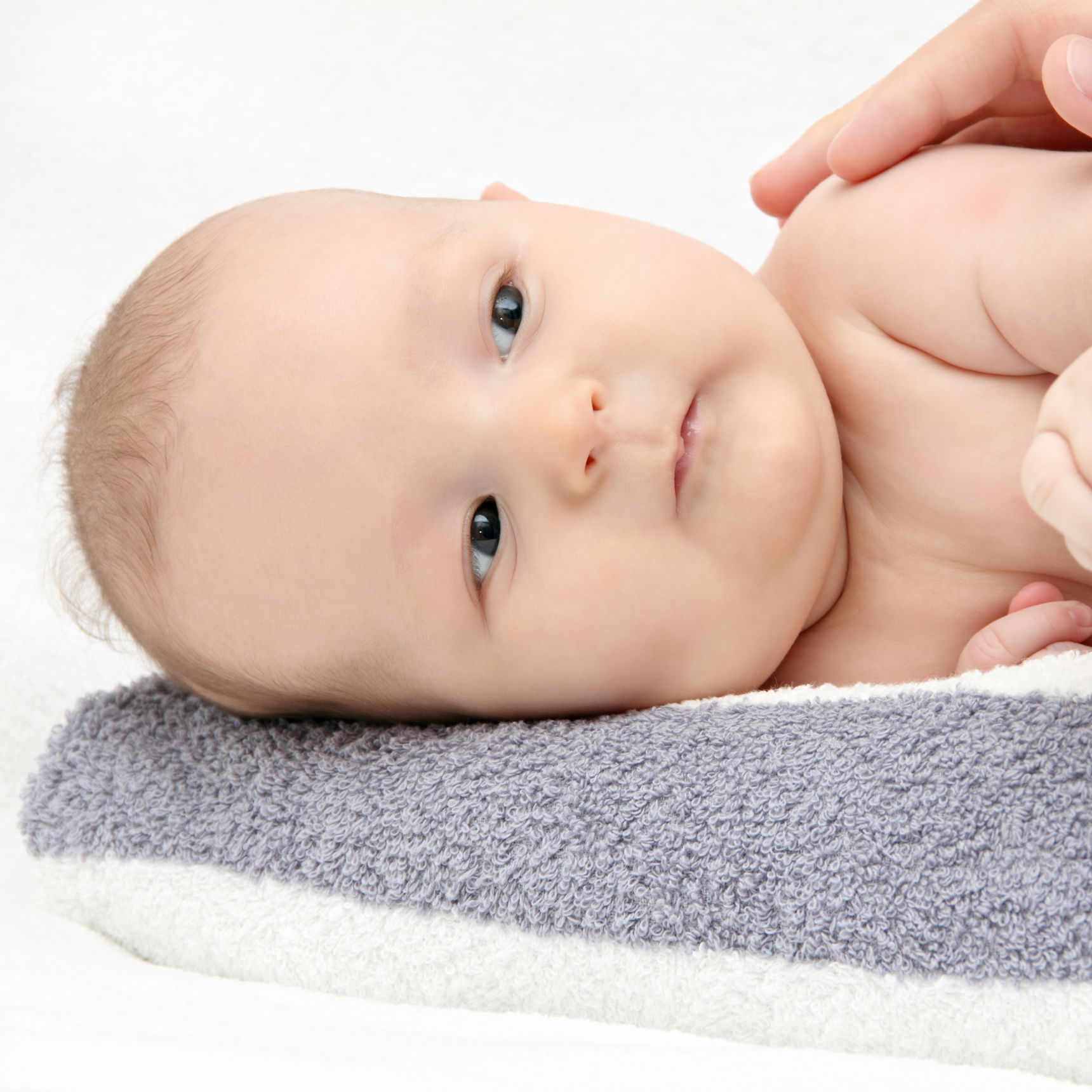 Baby der ligger på siden med en hånd hvilende på sig