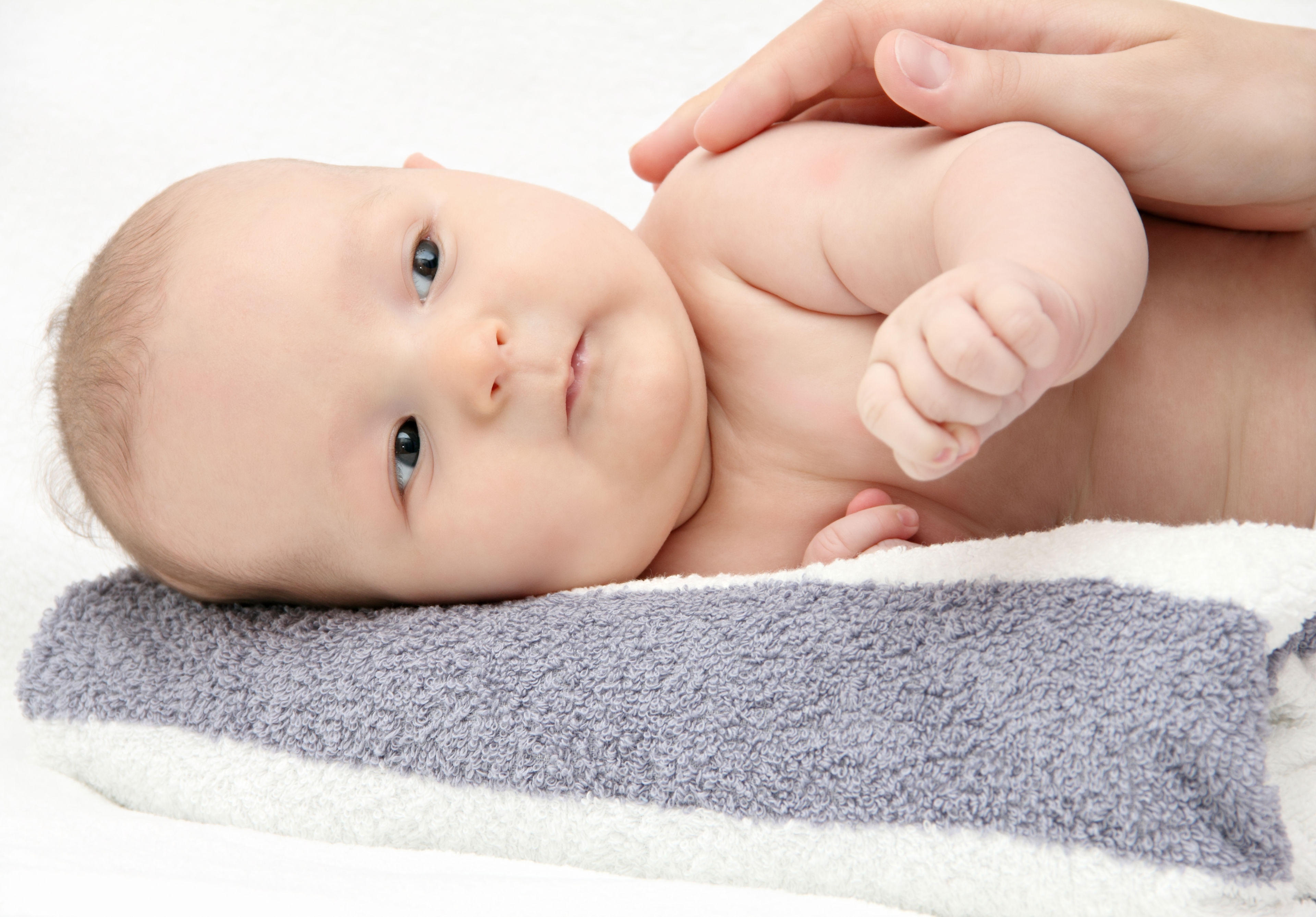 Baby der ligger på siden med en hånd hvilende på sig