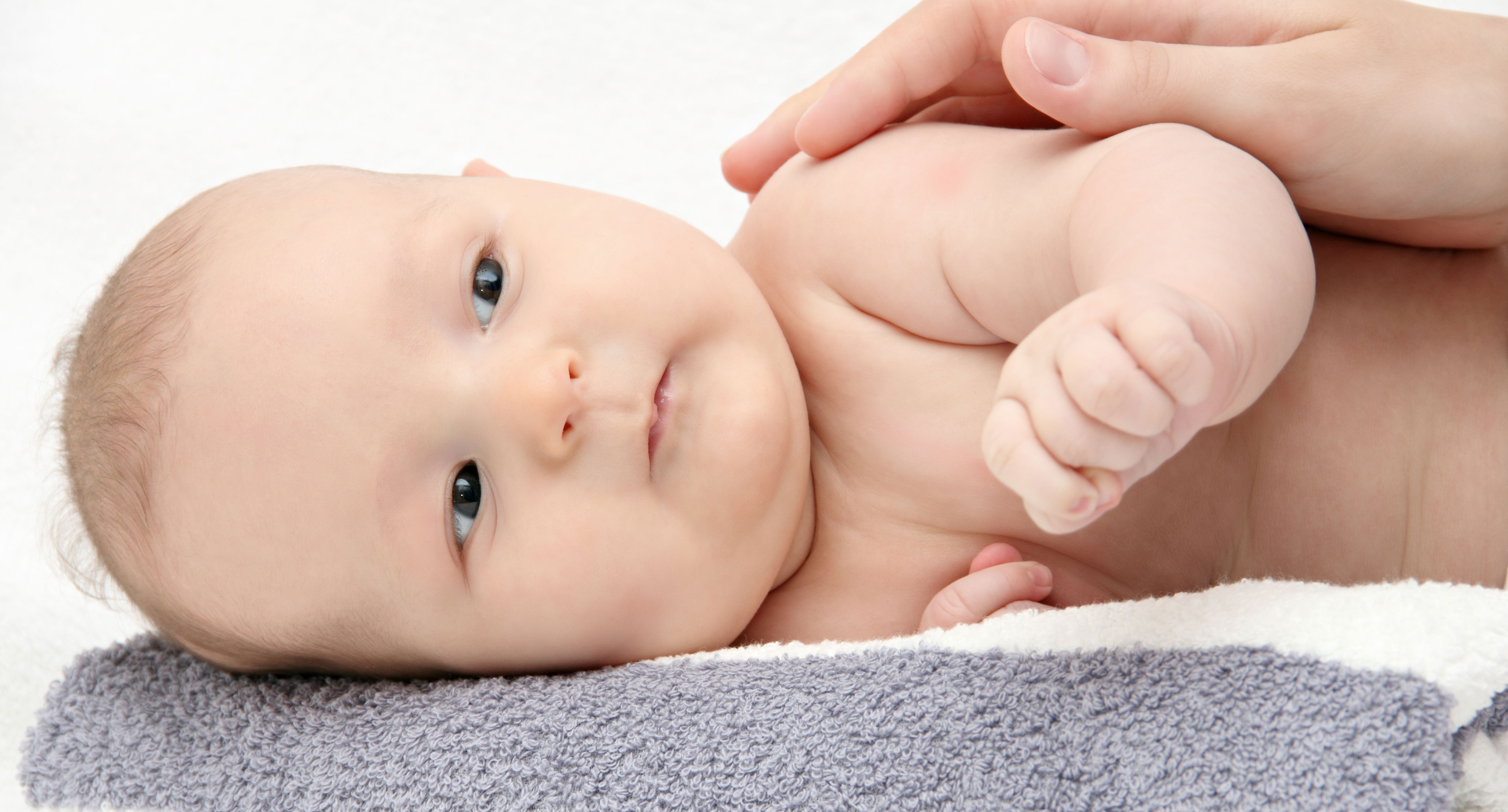 Baby der ligger på siden med en hånd hvilende på sig