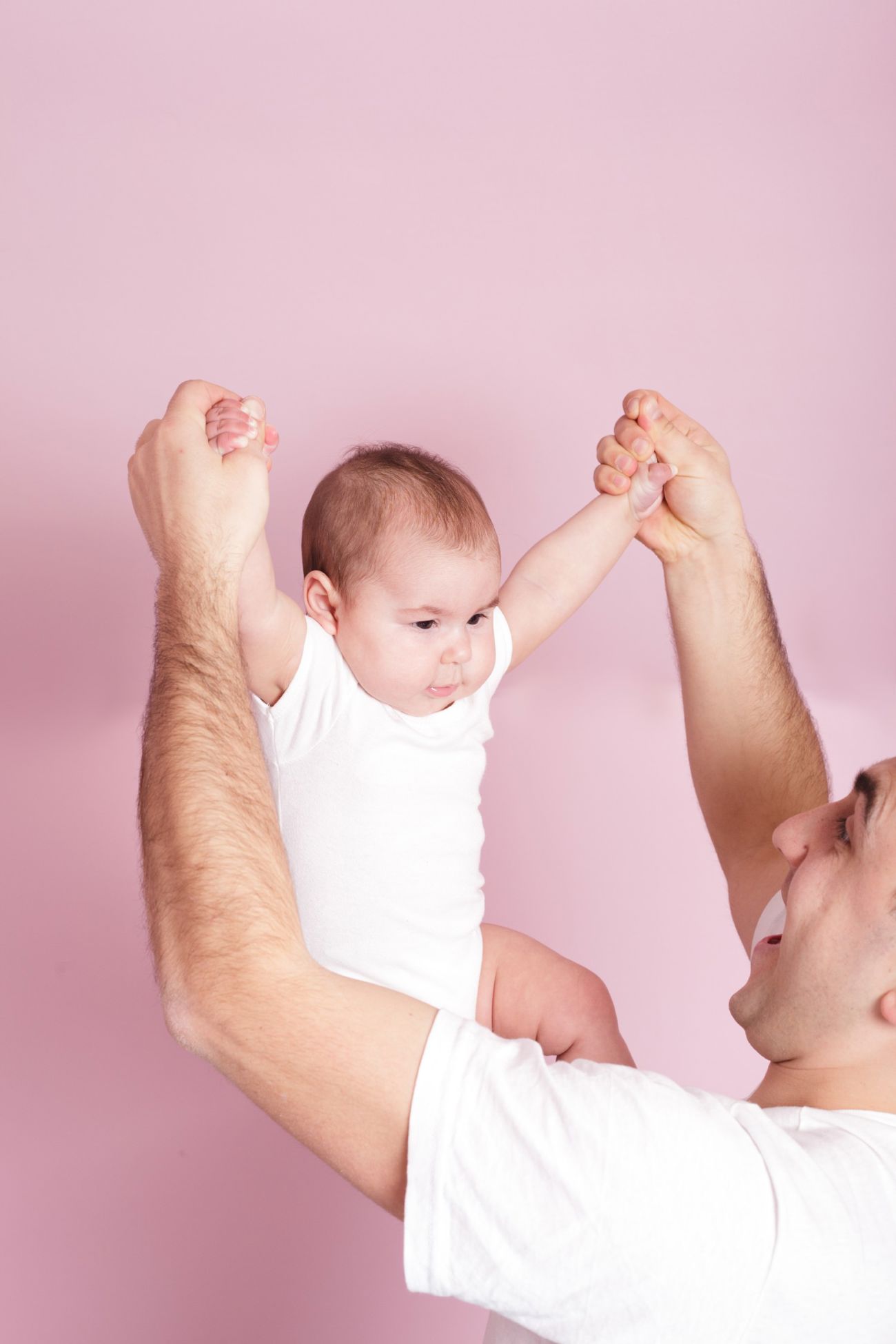 En far løfter sin baby op i armene