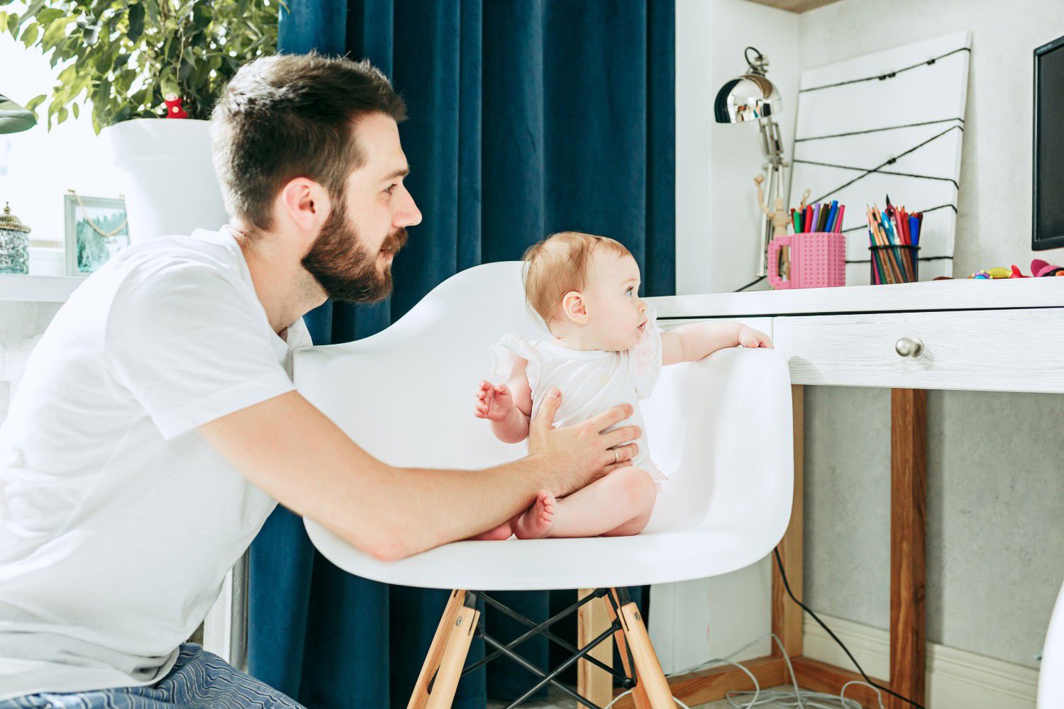 Baby sidder i en stol og snakker med sin far