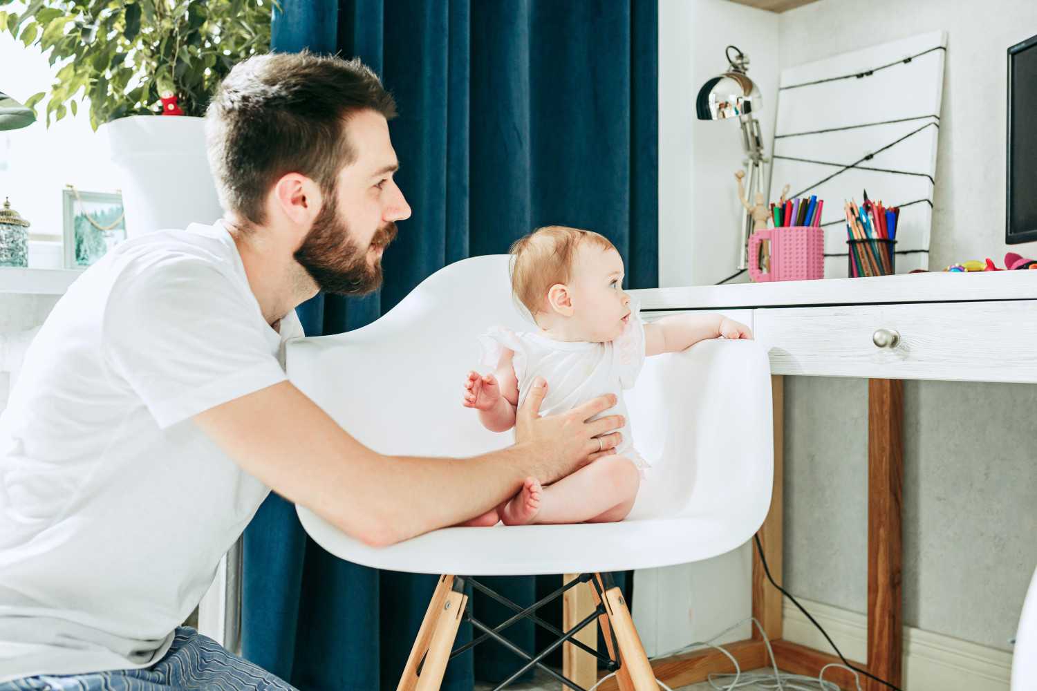 Baby sidder i en stol og snakker med sin far